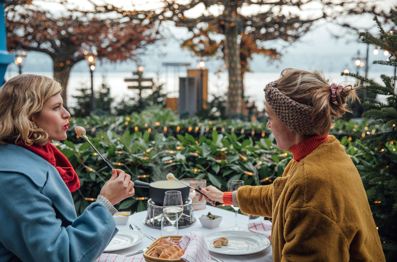 Zwei Freundinnen essen ein Fondue im Garten des Romantik Seehotel Sonne in Küsnacht.