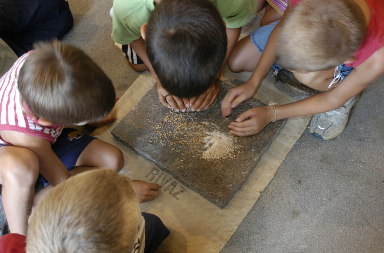 Kinder beim Mahlen auf einer Steinplatte