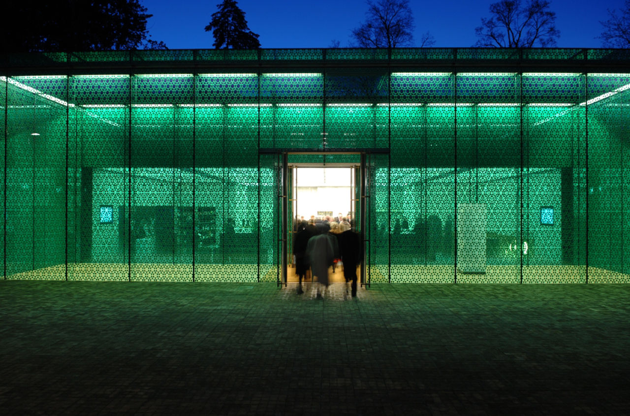 Eingangstüre des Museum Rietberg in Zürich. Menschen betreten Gebäude durch gläserne Fassade.