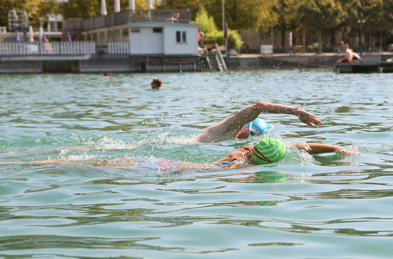 Zwei Personen schwimmen bei der Badi Utoquai in Zürich.